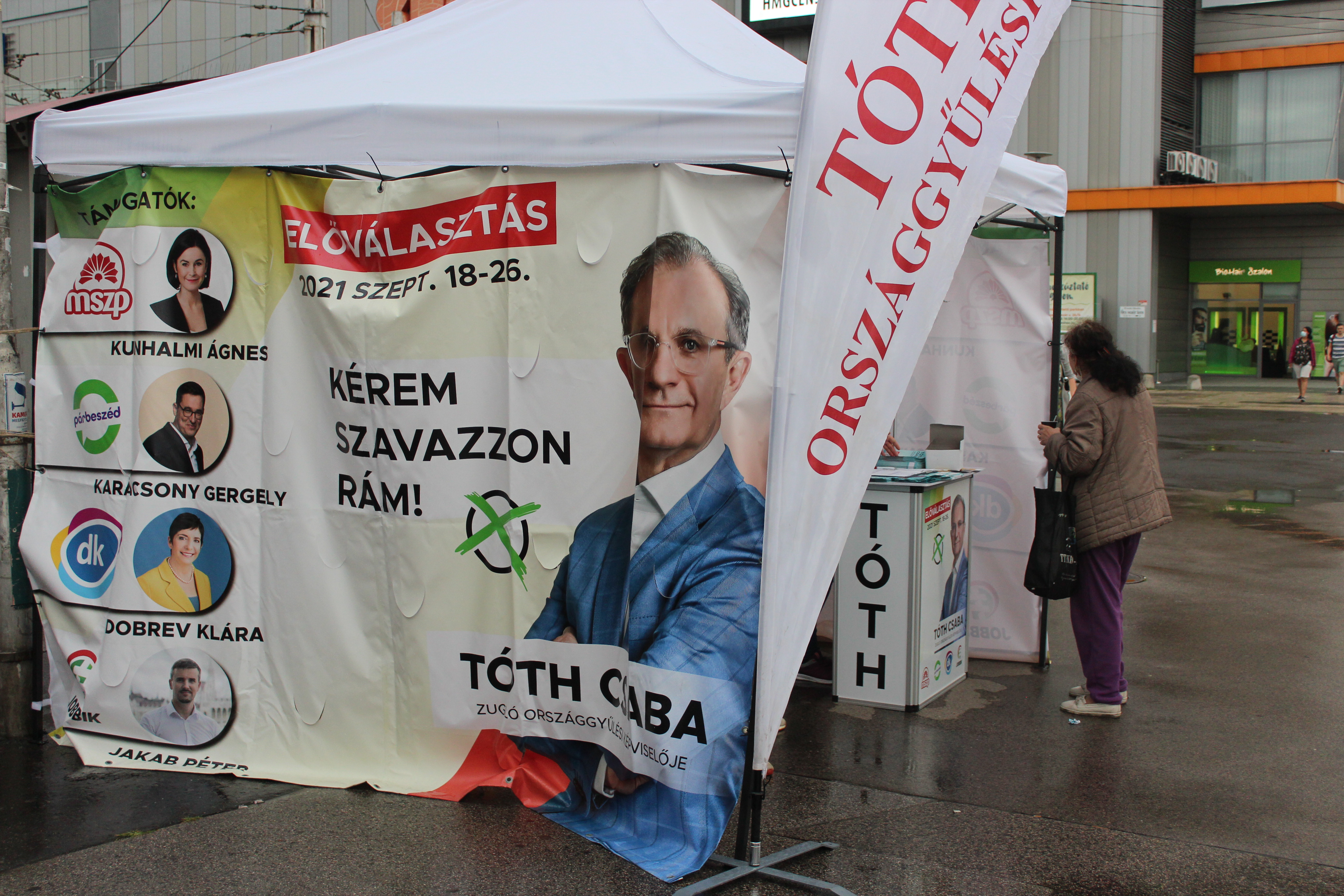 Tóth Csaba, az MSZP képviselőjelöltje támogatói arcképével kampányol, aktivistáit pedig sátorral védi a naptól és az esőtől.